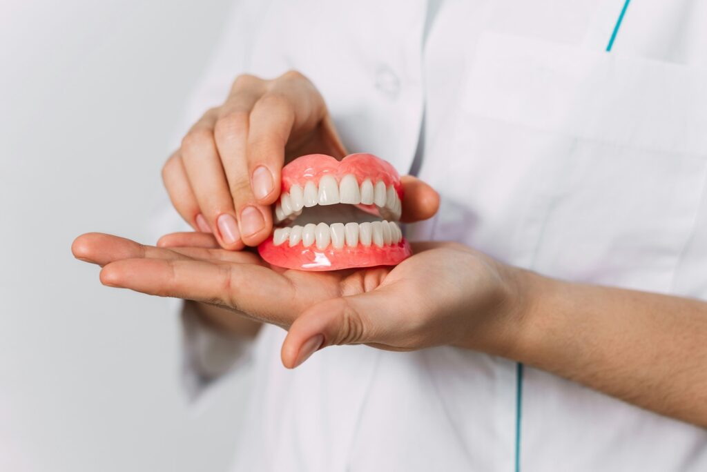 The dentist is holding dentures in his hands. Dental prosthesis in the hands of the doctor