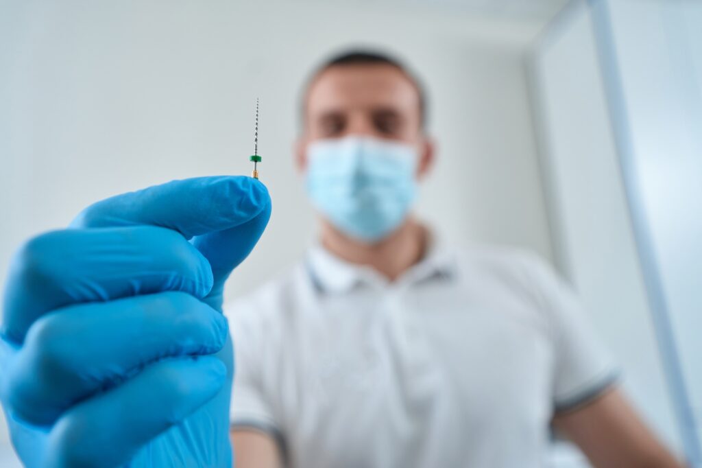 Dental professional showing medical tool for root canal treatment